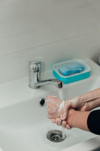 Cropped hand washing hands in sink