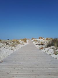 Surface level of footpath against clear blue sky