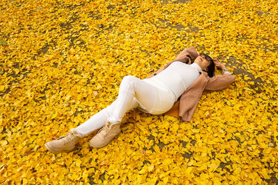 High angle view of woman lying down on yellow leaves