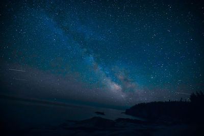 Scenic view of sea against star field in sky at night