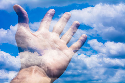 Double exposure image of hand against sky