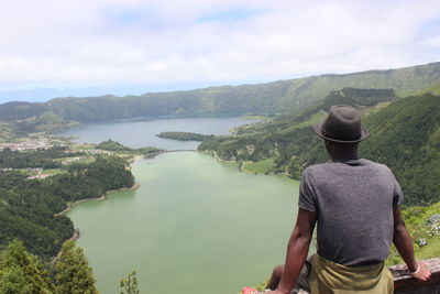 Rear view of man sitting against lake