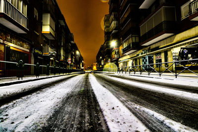 Illuminated railroad tracks in city against sky at night