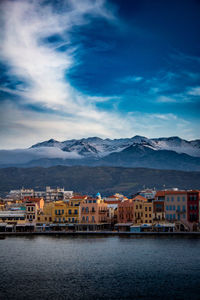 Buildings by river against sky