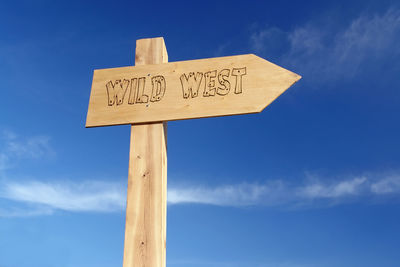 Low angle view of information sign on wooden post against blue sky