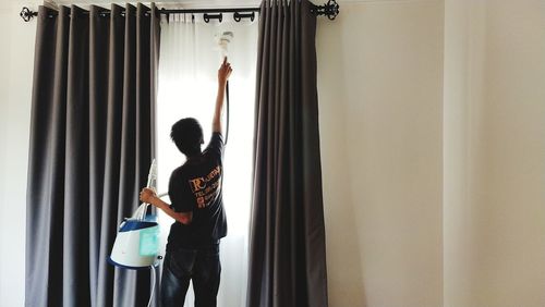 Man with arms raised standing against wall at home