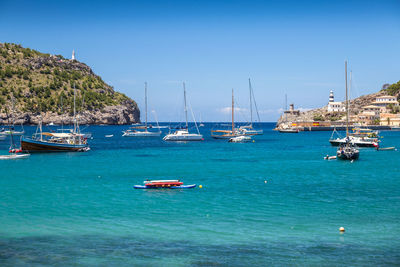 Sailboats moored on sea against clear blue sky