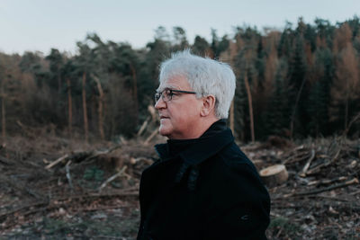 Portrait of man standing on field in destroyed forest