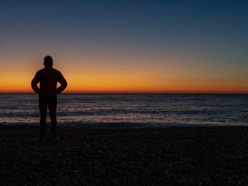 Silhouette man looking at sea against sky during sunset