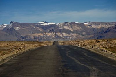 Road leading towards mountains against sky