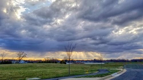 Road by landscape against storm clouds