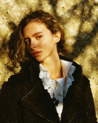 Portrait of young woman standing against wall