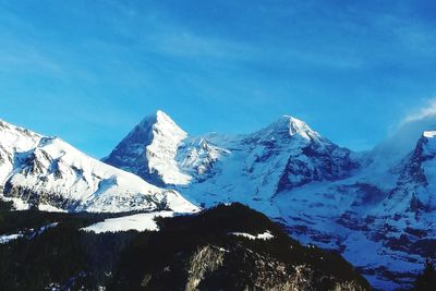 Scenic view of snowcapped mountains against blue sky