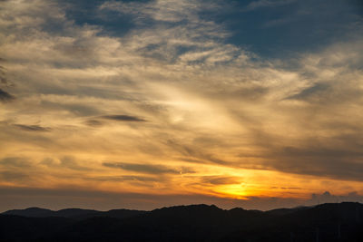 Scenic view of silhouette mountains against dramatic sky