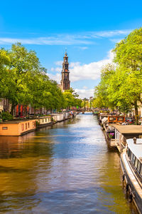 Canal amidst trees and buildings against sky