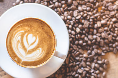 Close-up of frothy drink with roasted coffee beans on table