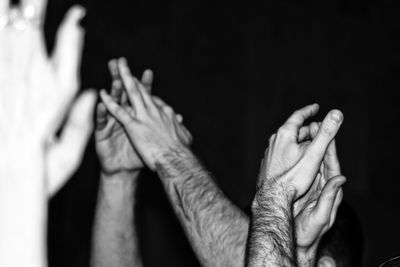 Cropped hands of people clapping against black background