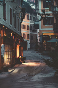 Illuminated street amidst buildings in city at night