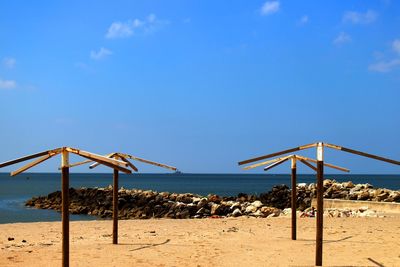 Scenic view of emoty beach umbrellas and sea against blue sky