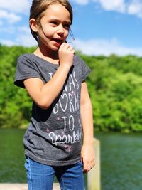 Girl looking away while standing by river