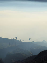 Low angle view of silhouette people on mountain against sky