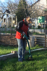 Woman using gardening equipment while standing in yard