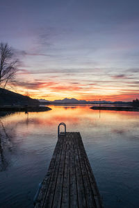 Pier over lake against sky during sunset