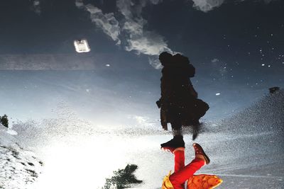 Low section of woman walking by puddle on wet road