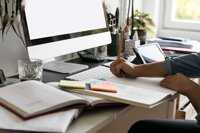 Cropped hands of businesswoman drawing on book at home