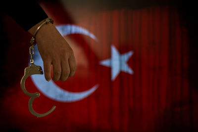 Cropped hand of male criminal with handcuffs against turkish flag