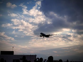 Low angle view of airplane flying against sky during sunset