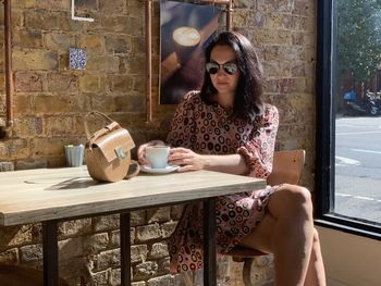 Young millennial woman is drinking morning coffee at a local cafe shop. sitting by the window