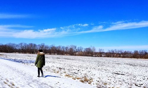 Rear view of woman walking on snow covered field
