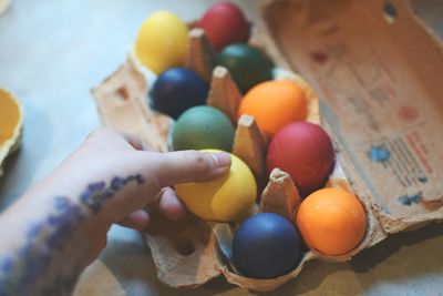 Cropped hand placing easter eggs in carton