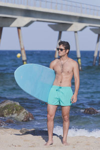 Shirtless man with surfboard at beach