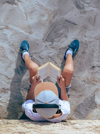 High angle view of boy sitting on sand at beach
