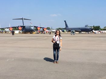 Woman with airplane on airport runway against sky