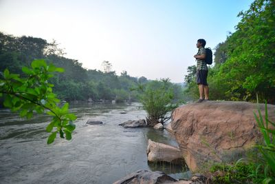 Man standing on rock against sky