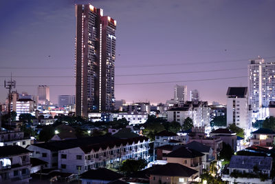 Illuminated buildings in city against sky at night