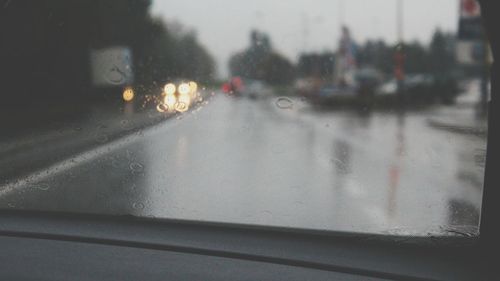 Cars on road seen through wet window during rainy season