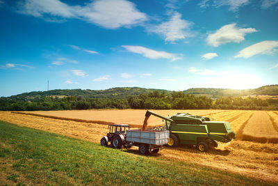 Agricultural machineries on field against sky