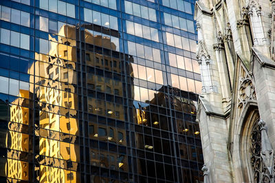 Low angle view of building reflection in modern office skyscraper by st patrick cathedral