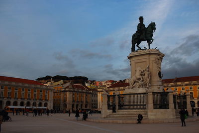 Statue in city against sky