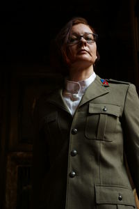 Mid adult woman standing against black background