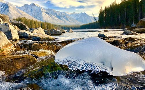 Scenic view of frozen lake by mountains against sky