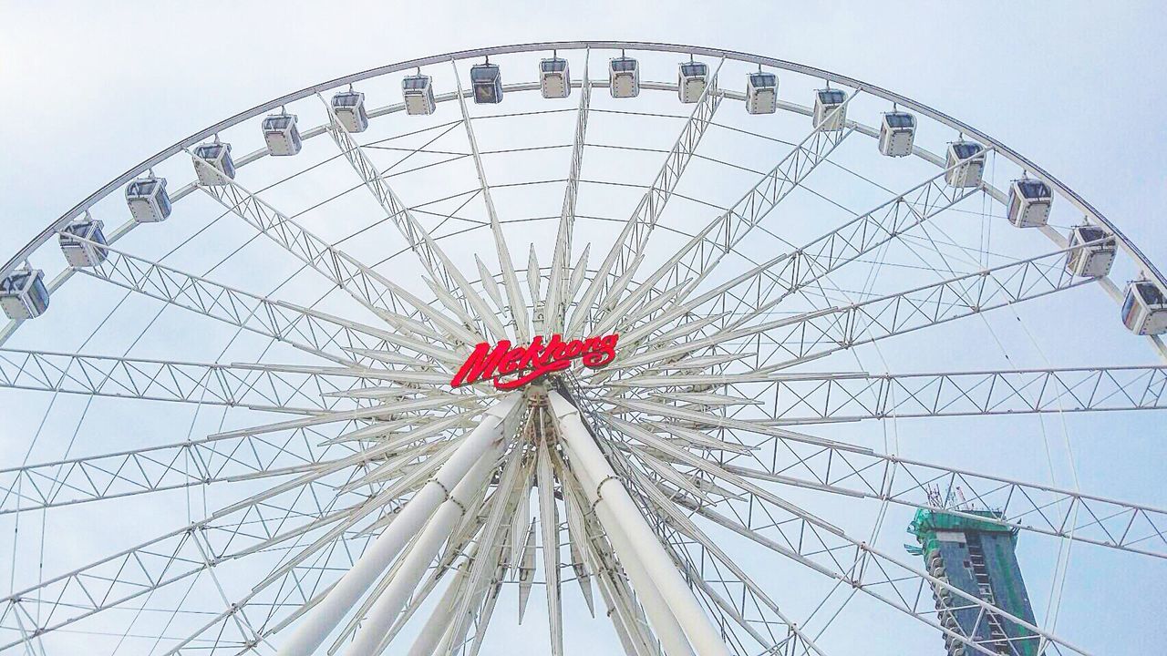 amusement park, amusement park ride, ferris wheel, low angle view, arts culture and entertainment, sky, fun, day, enjoyment, outdoors, travel destinations, no people, tourism, blue, part of, multi colored