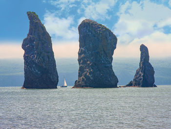 The sailboat sails near the coast and rocks on kamchatka peninsula