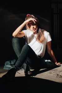 Young woman wearing sunglasses against black background