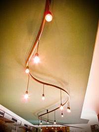 Low angle view of illuminated light bulbs hanging on ceiling