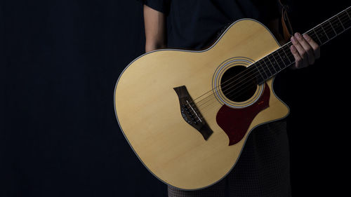 Close-up of playing guitar against black background
